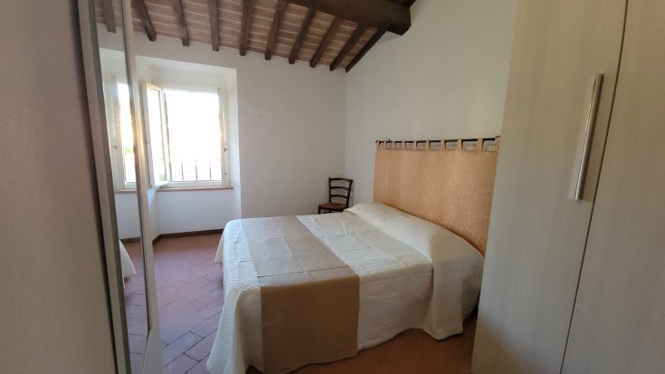 Une chambre confortable avec un lit double, une décoration simple et un éclairage chaleureux, offrant une vue depuis la fenêtre.