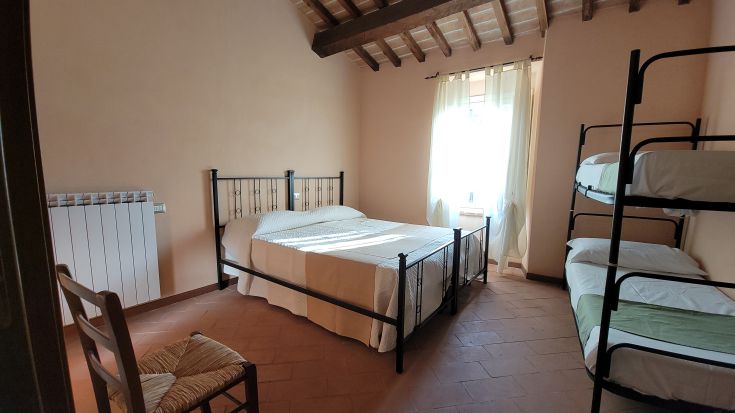 Chambre familiale spacieuse et bien éclairée, avec un lit double et des lits superposés, idéale pour les familles.