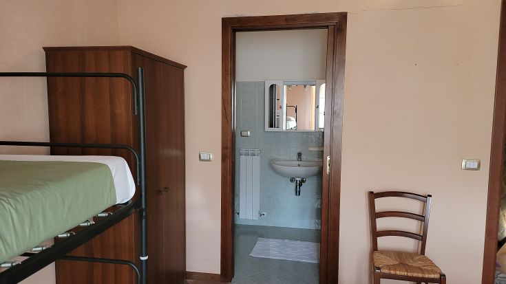 Chambre à l'intérieur d'un palais avec des lits superposés, une armoire et une salle de bain adjacente.