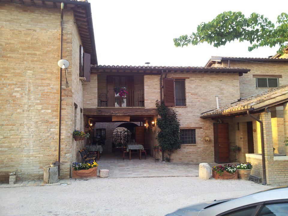 Agriturismo circondato da prati e alberi, con un casale recentemente ristrutturato.