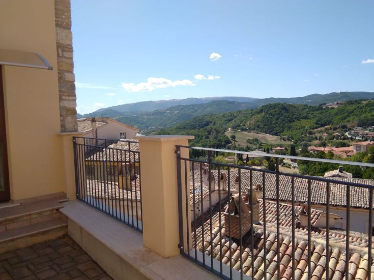 Un panorama sur la vallée avec les toits d'un village au milieu des collines verdoyantes.