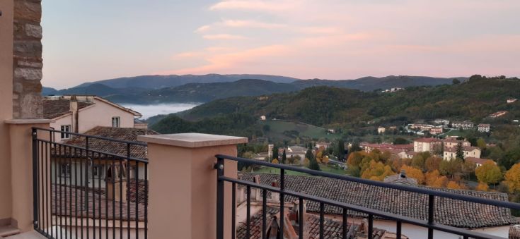 Un panorama de douces collines vertes sous un ciel au coucher de soleil, avec des nuages légers dessinant l'horizon.