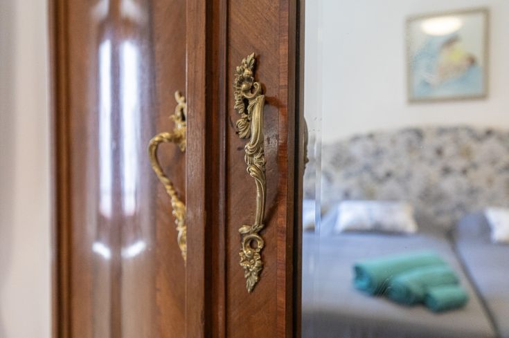 Un gros plan d'une armoire en bois avec une poignée dorée à l'intérieur d'une chambre confortable.