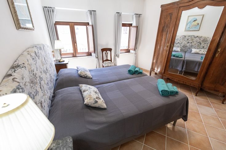 Chambre double simple avec lits jumeaux et mobilier fonctionnel, agrémentée d'un grand miroir.