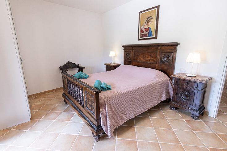 Chambre double simple avec des meubles en bois foncé et des tables de nuit. Un environnement calme et confortable.