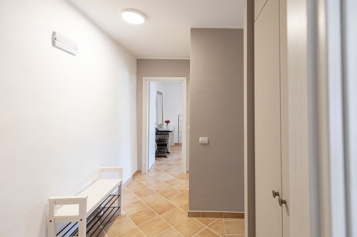 L'entrée présente un banc blanc et des murs clairs, créant une atmosphère accueillante.