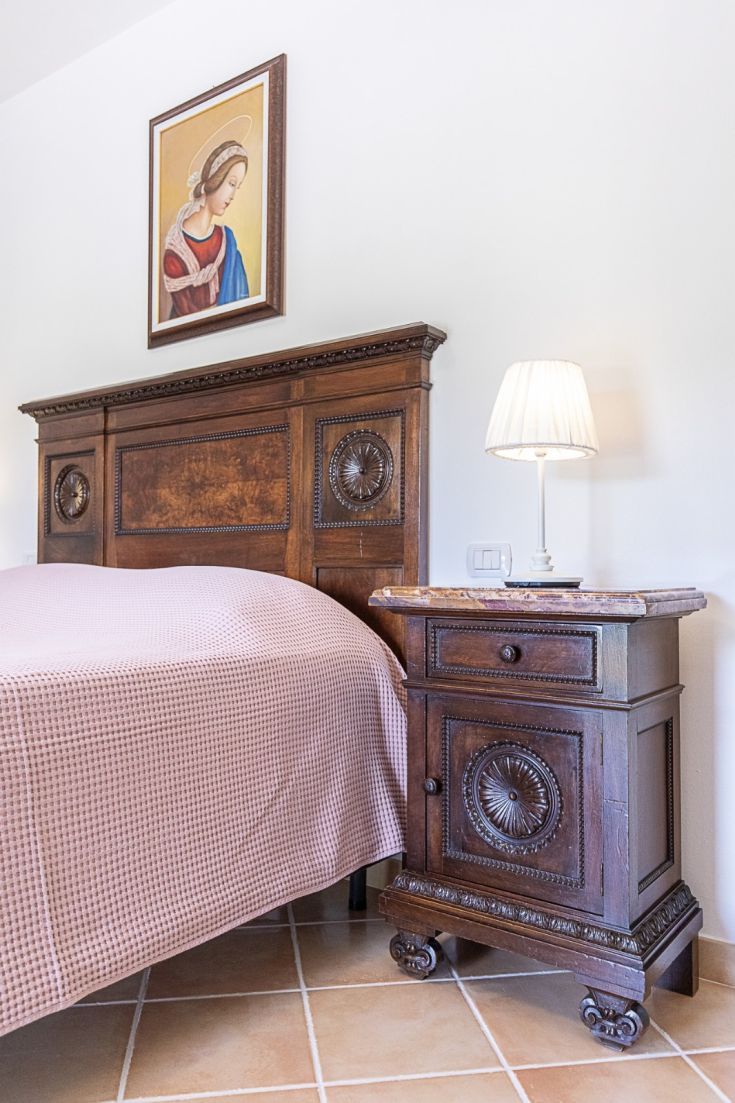 Une chambre double meublée avec des meubles en bois, une lampe simple et un tableau accroché au mur.