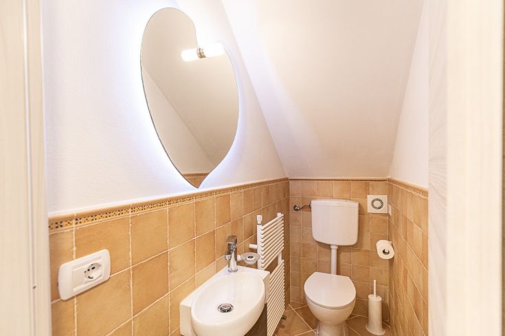 Une salle de bain au design sobre et accueillant, avec un miroir décoratif et des carreaux beiges.