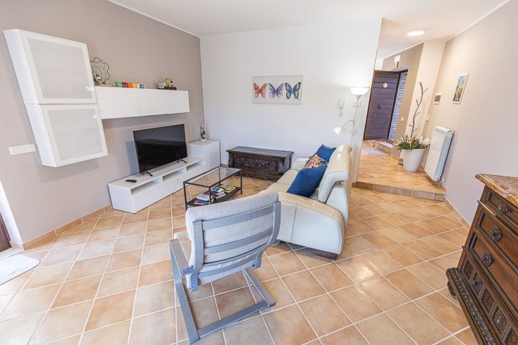 Salon lumineux avec un canapé, une télévision et des meubles contemporains, idéal pour des moments de détente.