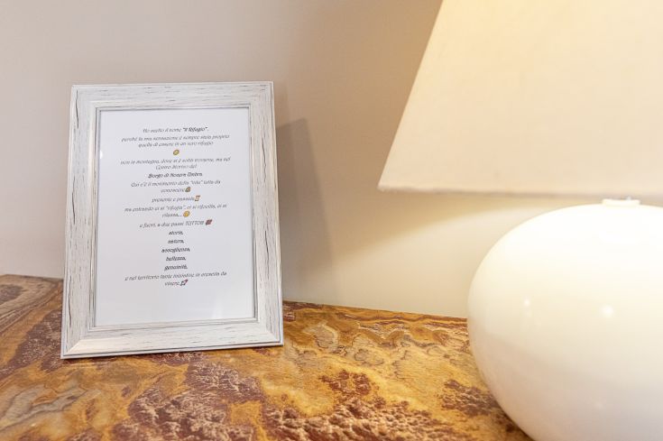 Un tableau encadré avec un texte poétique posé sur une table à côté d'une lampe allumée.