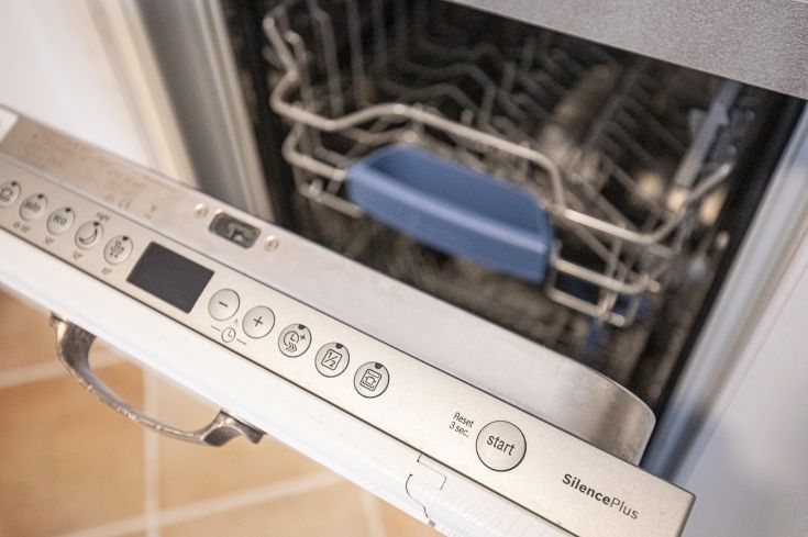 Gros plan sur un lave-vaisselle avec panneau de contrôle et panier, conçu pour faciliter le nettoyage à la maison.