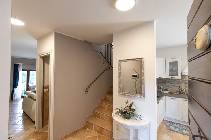 Entrée avec escalier menant à la cuisine et au salon, avec accès à des espaces extérieurs privés.