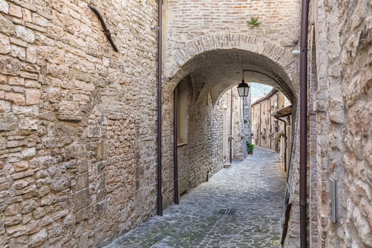 Allée en pierre avec un lampadaire et des bâtiments historiques, idéale pour une promenade dans le coin.