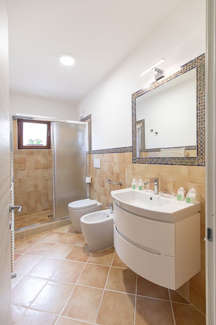 Salle de bain moderne au design simple, bien éclairée, avec douche, lavabo et WC dans un style pratique.
