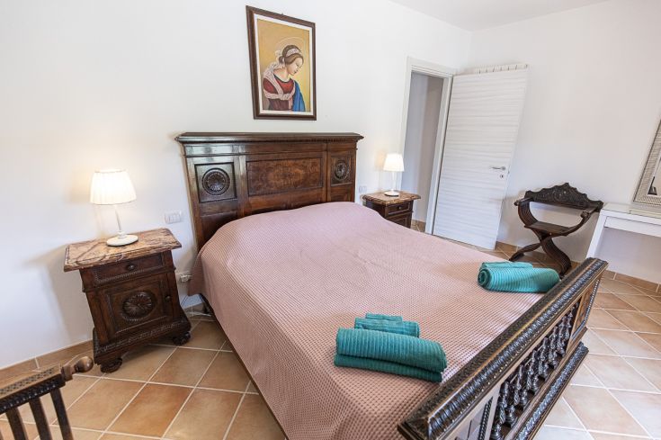 Chambre simple avec un lit en bois et des décorations. Espace accueillant et confortable.