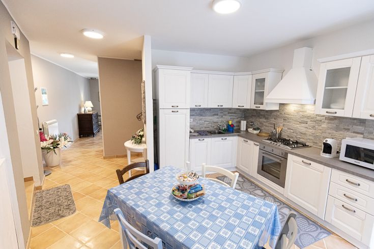 Cuisine contemporaine et fonctionnelle avec une table, des appareils électroménagers et un accès à un jardin pavé.