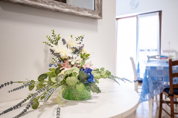 Un vase décoratif avec des fleurs artificielles sur une table, ajoutant une touche de fraîcheur à l'environnement.