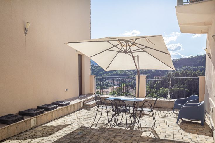 Terrasse extérieure équipée d'une table et d'un parasol, idéale pour des moments de détente à l'extérieur.