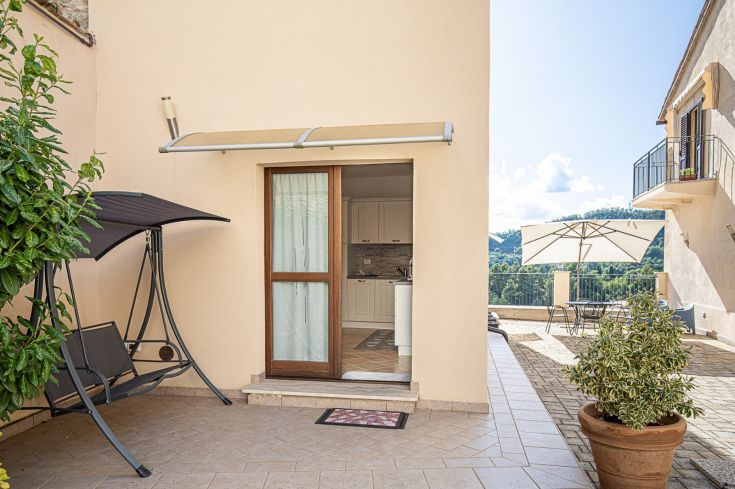 Espace extérieur meublé de plantes, avec des zones de sièges confortables.