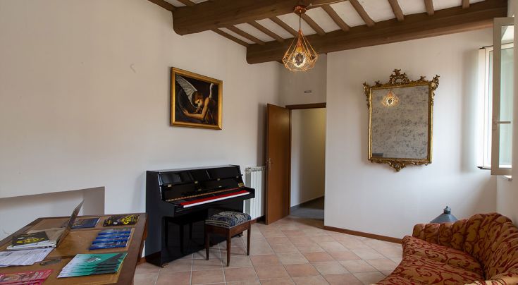 Soggiorno composto da un pianoforte e arredi semplici, con elementi storici a Perugia.