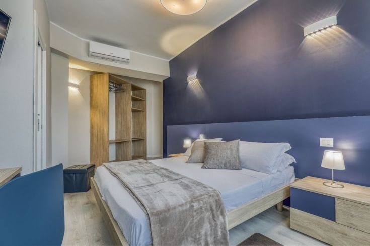Simple room with light wood furniture and blue tones; features air conditioning and TV.