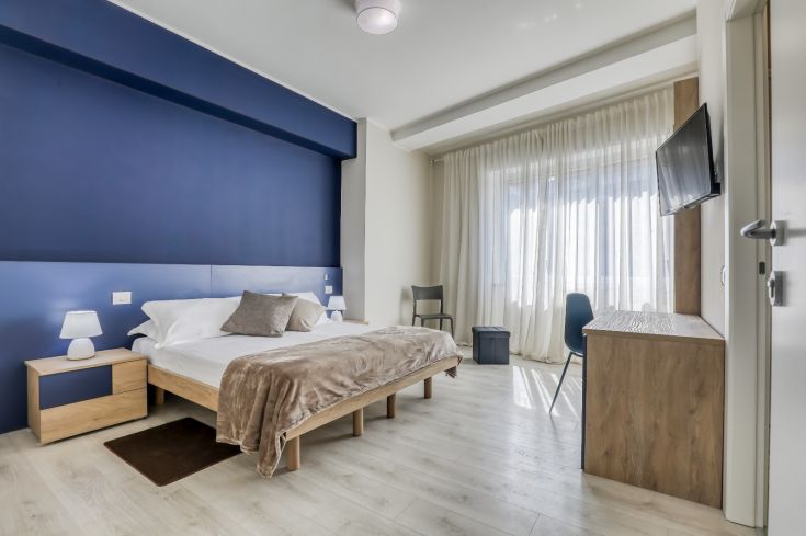 Cozy space with light wooden furniture and blue decorations, well-lit and suitable for short stays.