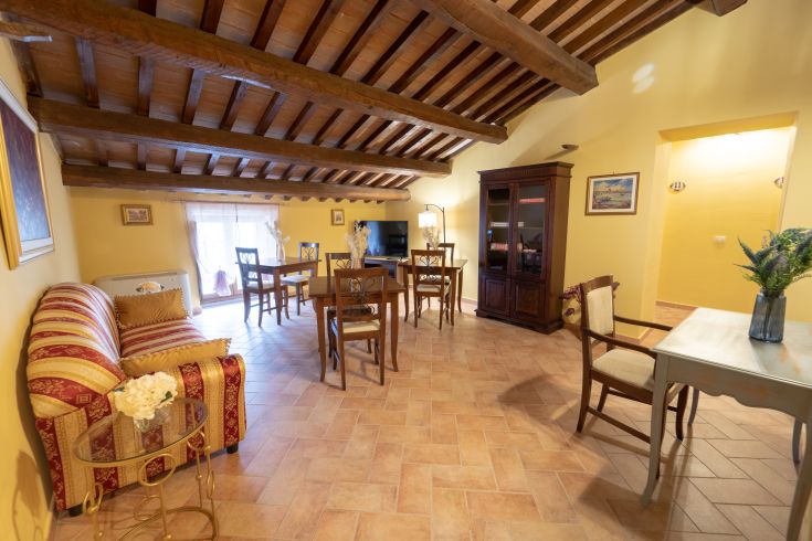 Soggiorno confortevole con soffitto in legno e arredamento sobrio, adatto per trascorrere momenti di relax.