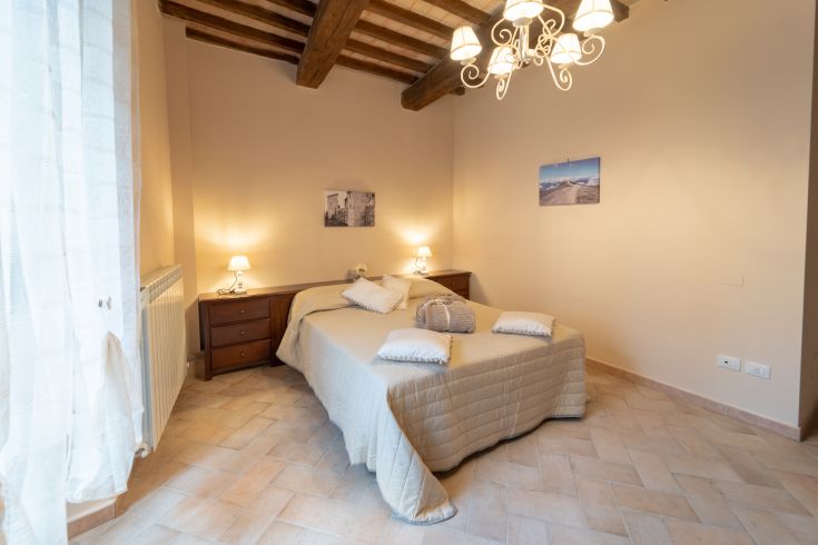 Camera moderna e ben illuminata, con elementi rustici e comfort essenziali per un soggiorno piacevole.