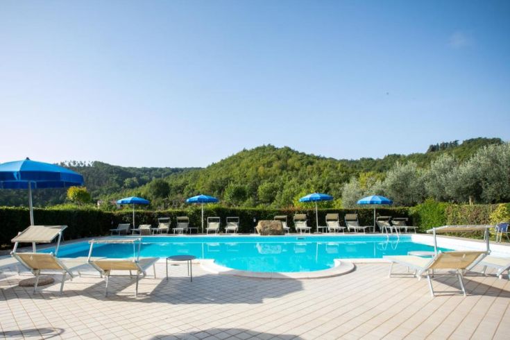 Une piscine entourée de pelouses vertes et de douces collines, idéale pour des moments de détente et de tranquillité.
