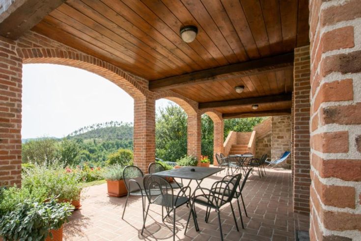 Espace extérieur confortable entouré de verdure, avec des meubles rustiques pour se détendre.