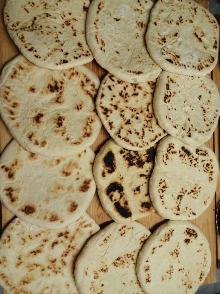 Focacce ben dorate e cotte, disposte ordinatamente su un tagliere di legno chiaro.