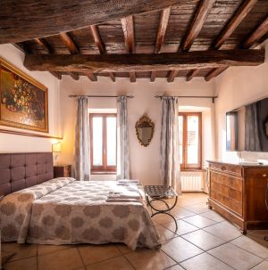 Ambiente matrimoniale con soffitto in legno e mobili sobri, adatto per un soggiorno confortevole.