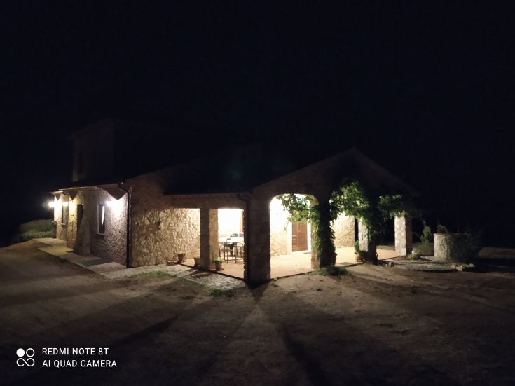 Casale in pietra illuminato di notte, con un'atmosfera accogliente e uno scenario tranquillo.