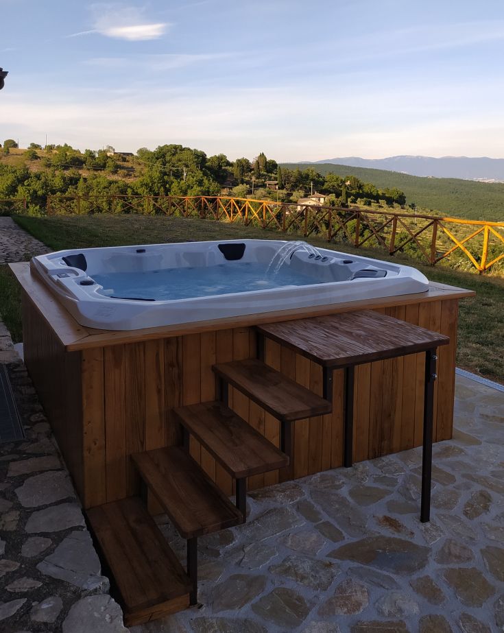 Vasca idromassaggio circondata da piante, ideale per momenti di relax e per godere della vista del giardino.