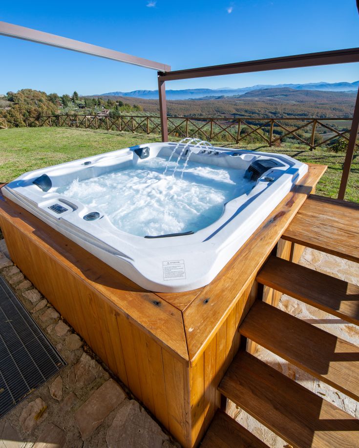 Vasca idromassaggio esterna, circondata dalla vegetazione, in un ambiente tranquillo e rilassante.