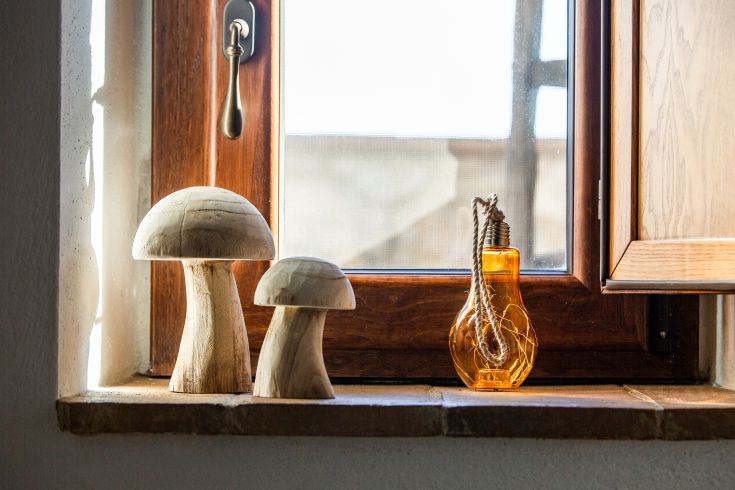 Decorazione in legno e una bottiglia arancione su un davanzale di una finestra illuminata.