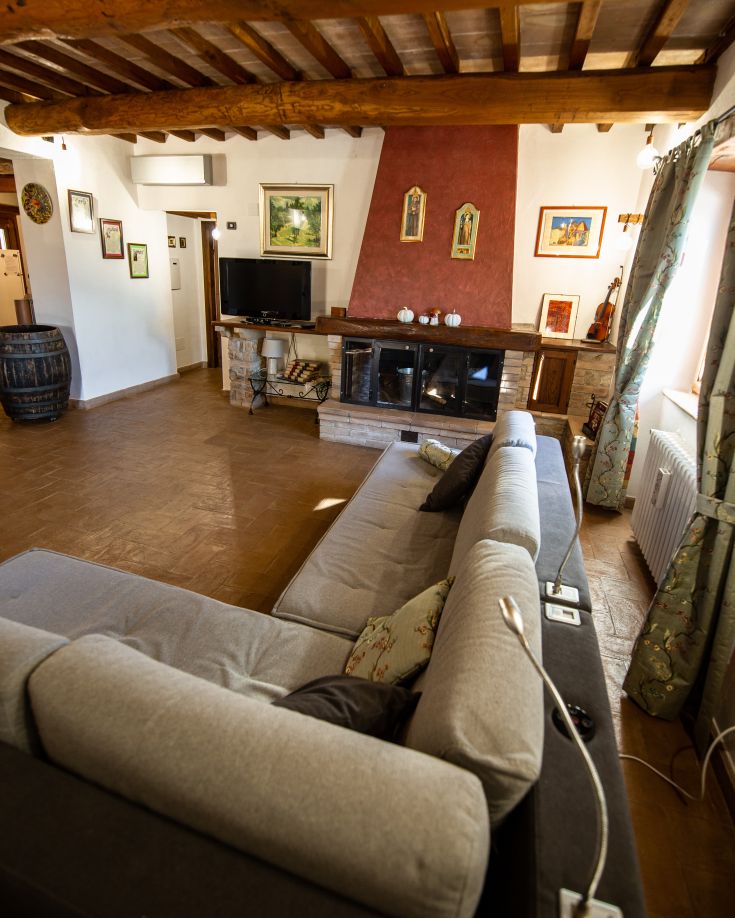 Soggiorno semplice in un casale caratterizzato da strutture in legno e decorazioni soft.