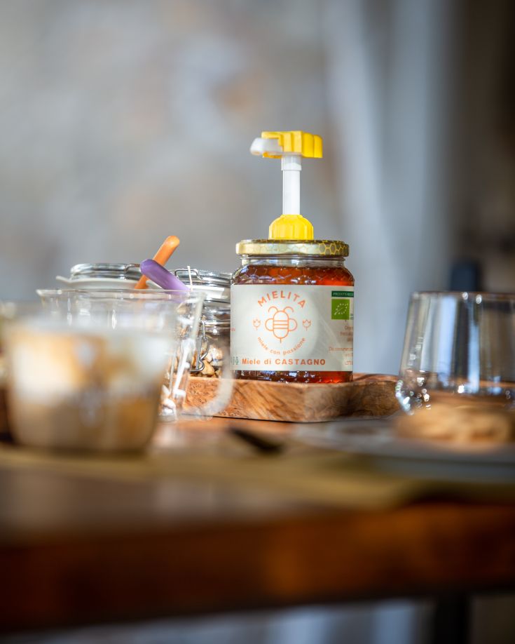 Barattolo di miele di castagno posizionato su un tavolo semplice, adatto per arricchire la colazione.