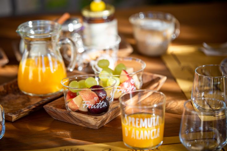 Un tavolo allestito con frutta fresca e succo d'arancia, ideale per una colazione leggera e nutriente.