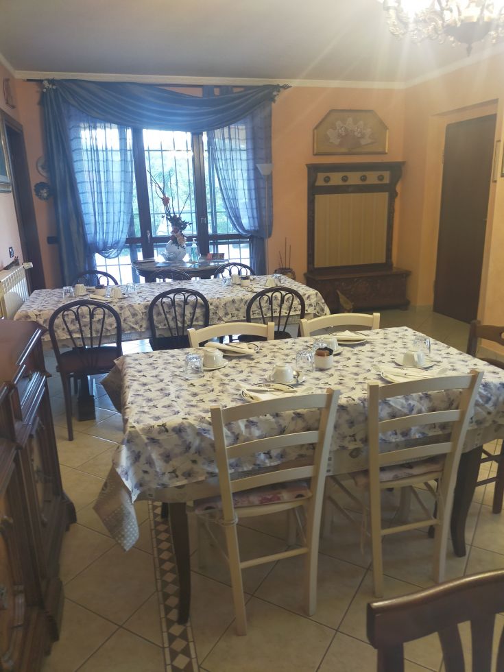 Spacious dining room with simple tables, illuminated by natural light from the windows.