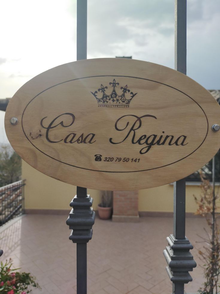 A simple and welcoming wooden sign for Casa Regina, a place of relaxation.
