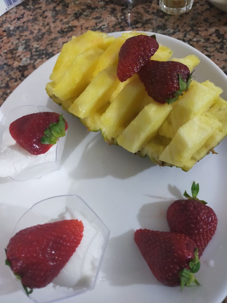 A fresh dessert made of slices of pineapple and strawberries, perfect for summer.