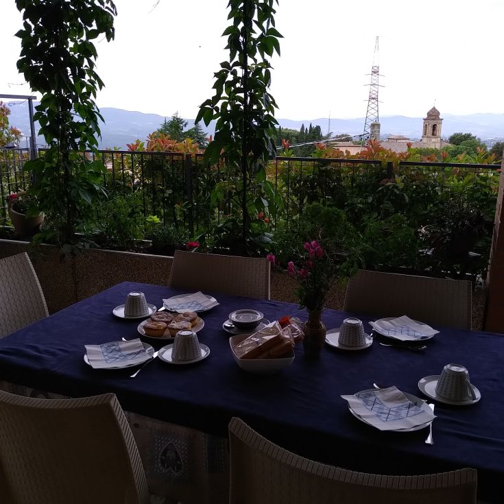 A breakfast table set with a selection of food and drinks, located in a green and peaceful area.