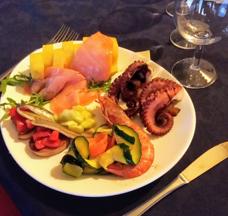 A plate of fresh fish, served with vegetables and fruits, perfect for seafood lovers.
