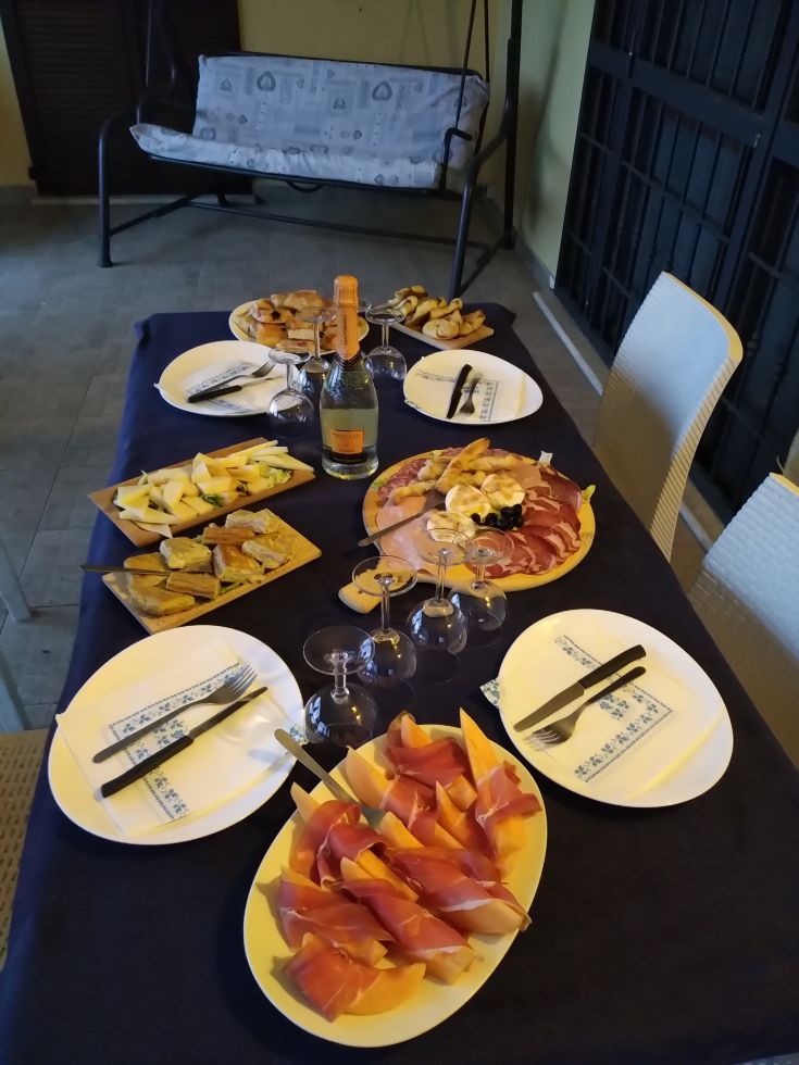 A table set with a selection of appetizers, cured ham, cheeses, and sparkling wine, ready for a night with friends.