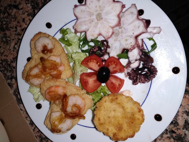 A plate of fried shrimp and octopus, served with mixed salad and fresh tomatoes.