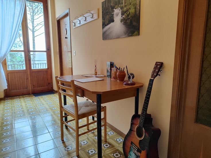 A relaxing study corner with a table and guitar, surrounded by nature.