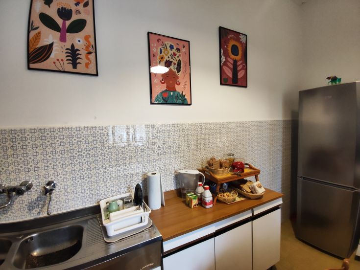 A modern kitchen with colorful touches, furnished with posters and functional items.