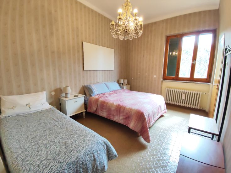 Spacious and cozy room with two beds and a stylish chandelier.