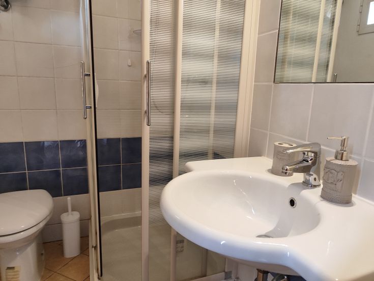 A modern bathroom featuring a shower and sink, with simple details and sleek finishes.